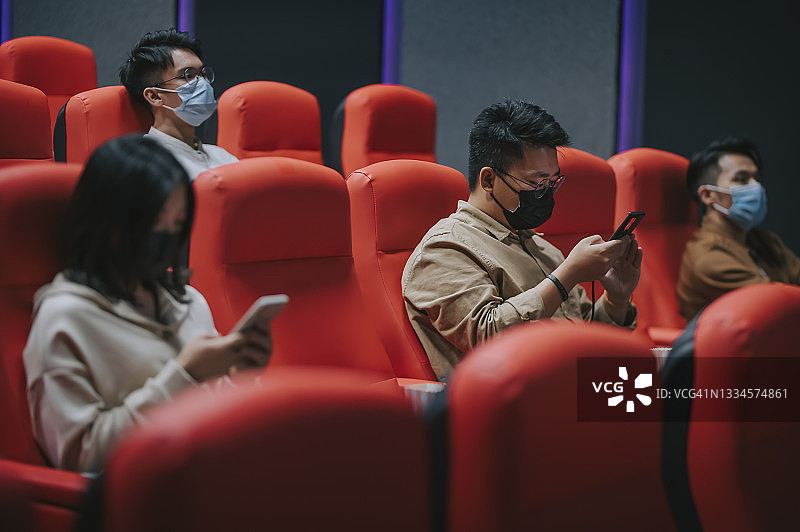 不同年龄段的中国人在电影院等待电影放映时使用智能手机图片素材