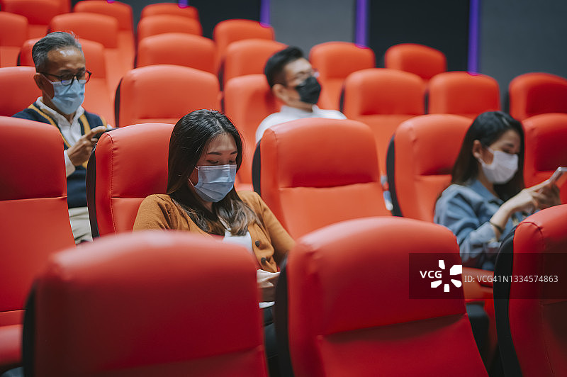 不同年龄段的中国人在电影院等待电影放映时使用智能手机图片素材