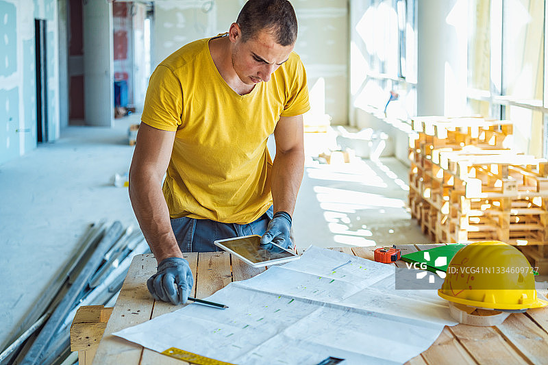 身穿工作服的建筑工人或工头，在室内建筑工地拿着蓝图鉴定结构图片素材