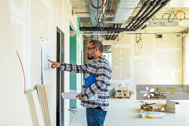 在工业建筑工地研究蓝图的英俊工头图片素材