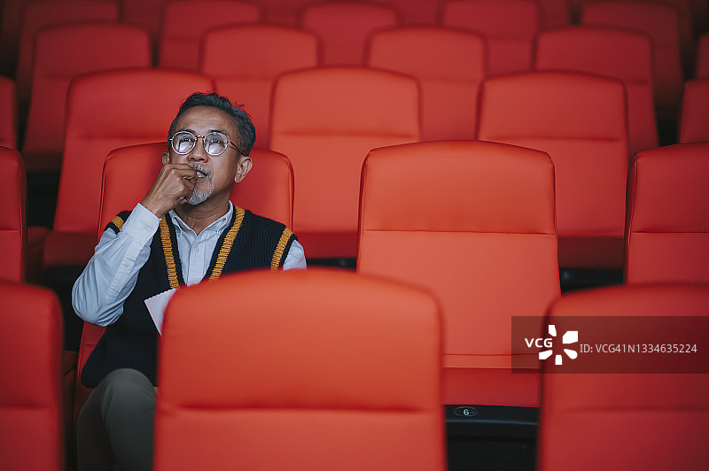 中国老年男人在电影院看电影吃零食图片素材