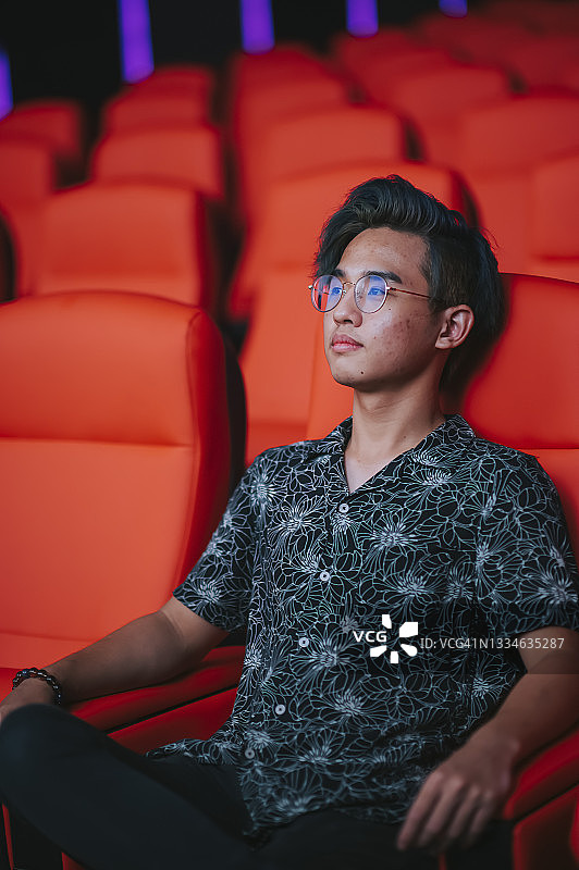 独自在电影院看电影的亚洲少年图片素材