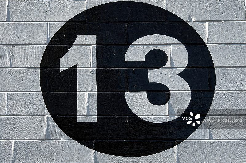 白色砖墙上黑色圆圈内的134号街牌图片素材