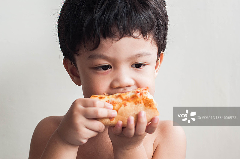 一名东南亚幼儿正在吃披萨图片素材