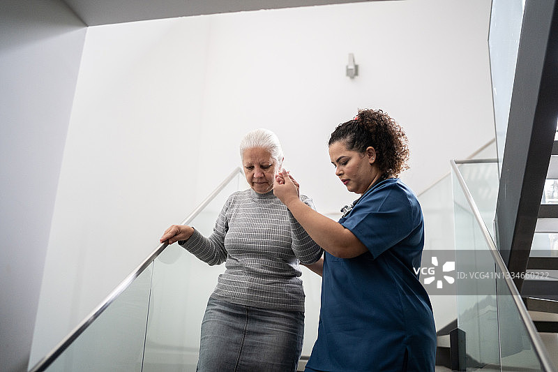 家庭护理员帮助老年妇女在家中下楼梯图片素材