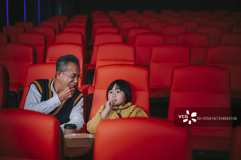 亚洲华人老年夫妇和孙女在电影院看电影图片素材
