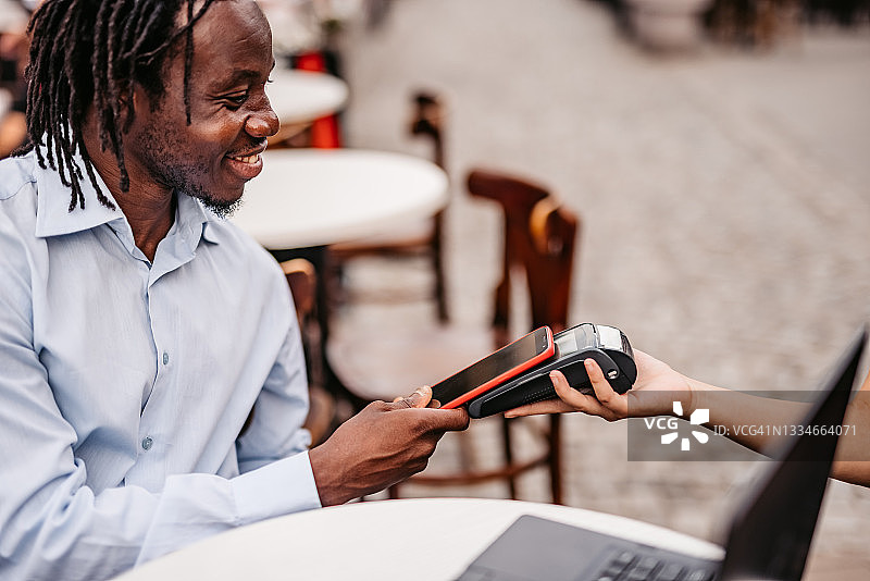 在咖啡馆用智能手机非接触式支付图片素材