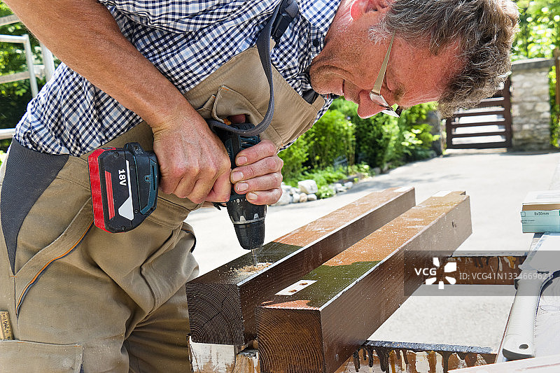 木匠在木柱上钻孔图片素材