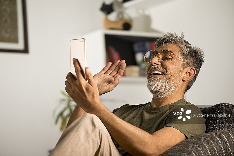在家使用平板电脑进行视频聊天的男人图片素材