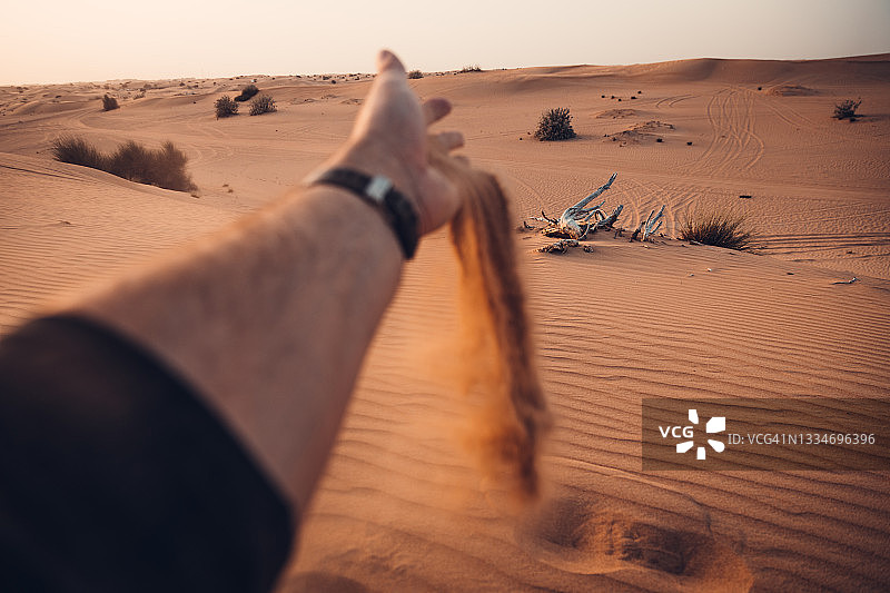 男人在沙漠中倾倒沙子图片素材