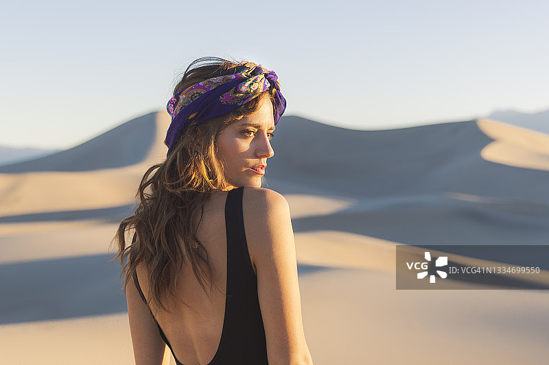 站在金色光芒沙丘中的美丽女人图片素材