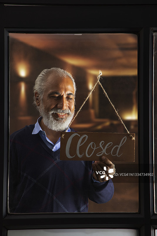 老人挂着已关闭的告示牌图片素材