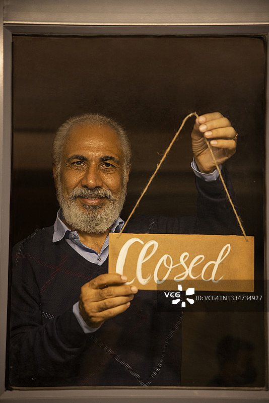 一位老人拿着关闭告示牌图片素材