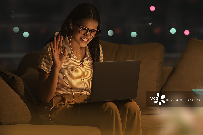 一位戴着眼镜的年轻女子开心地进行视频会议图片素材