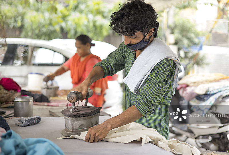 戴着口罩熨烫衣服的工人图片素材