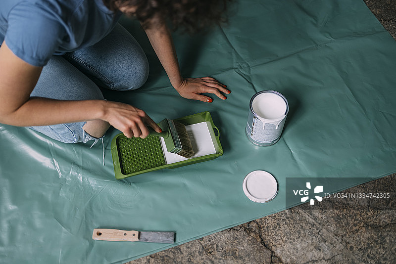 DIY家居改造：匿名女子将画笔浸入白色油漆中图片素材