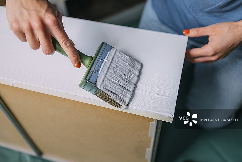 DIY家居翻新：匿名女人将家具漆成白色图片素材