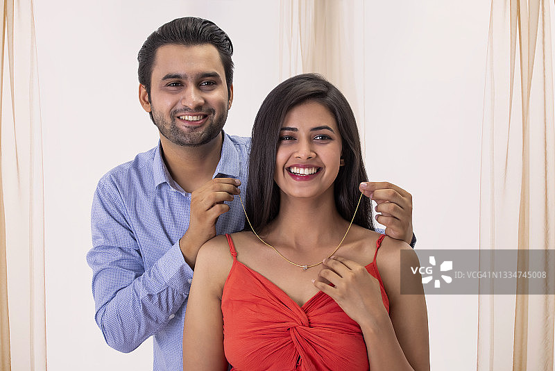 男子将吊坠项链戴在妻子脖子上图片素材