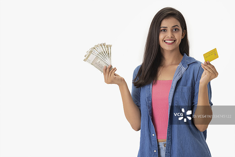 年轻女子手持信用卡和现金图片素材