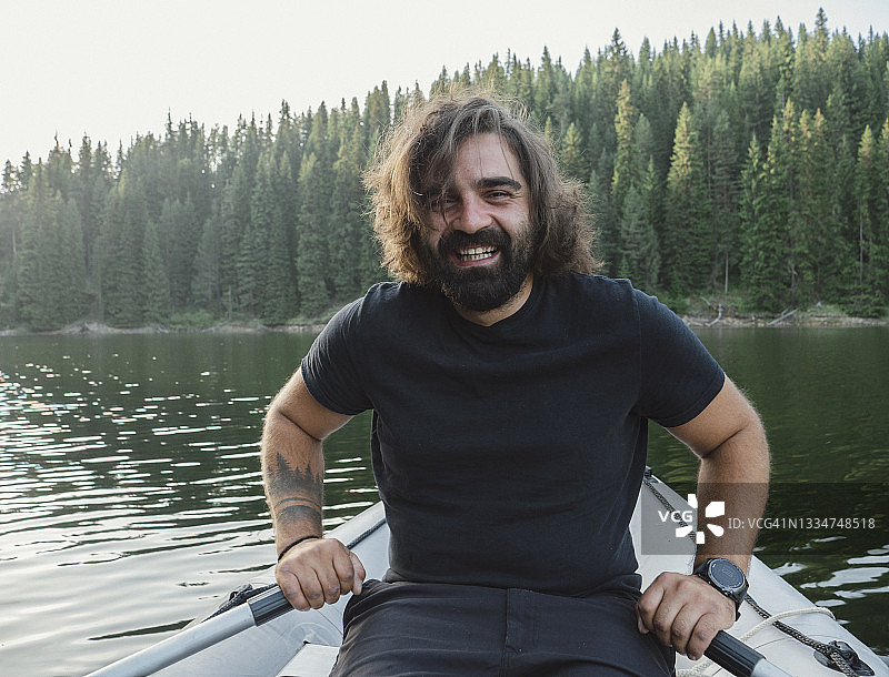 在湖中划桨的年轻男人肖像图片素材