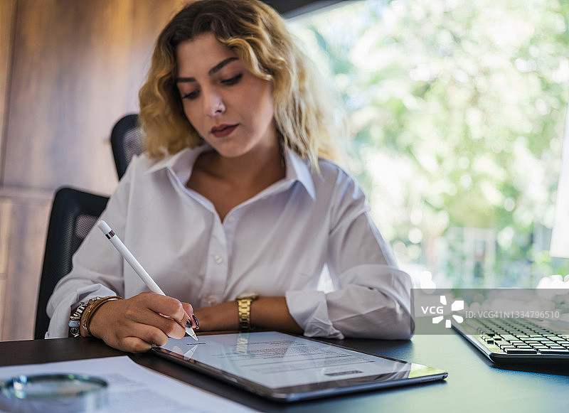 女商人使用平板电脑在办公室签署法律文件图片素材