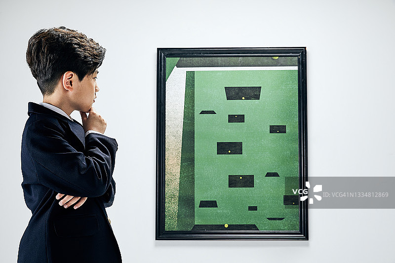 穿西装的男孩看着艺术品图片素材