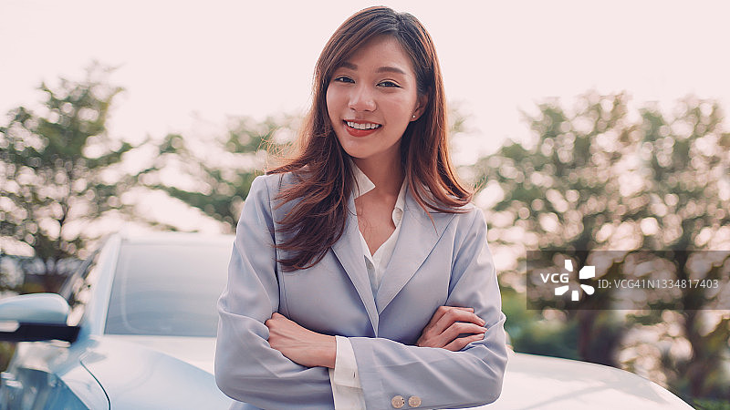 女商人站在充电电动汽车旁图片素材