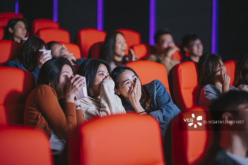 一群中国人在电影院里观看恐怖电影，遮住脸庞图片素材