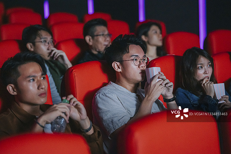 一群中国年轻人在电影院观看恐怖电影，遮住脸图片素材