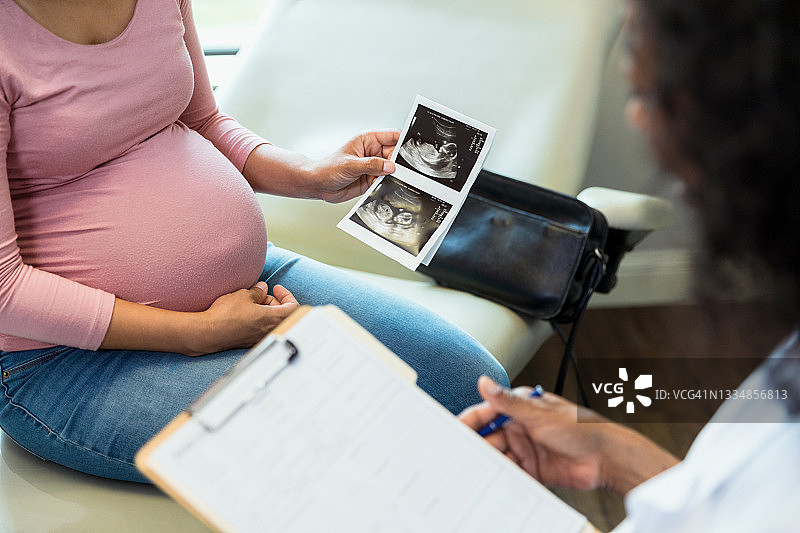 不露脸的孕妇和女产科医生讨论超声波检查结果图片素材