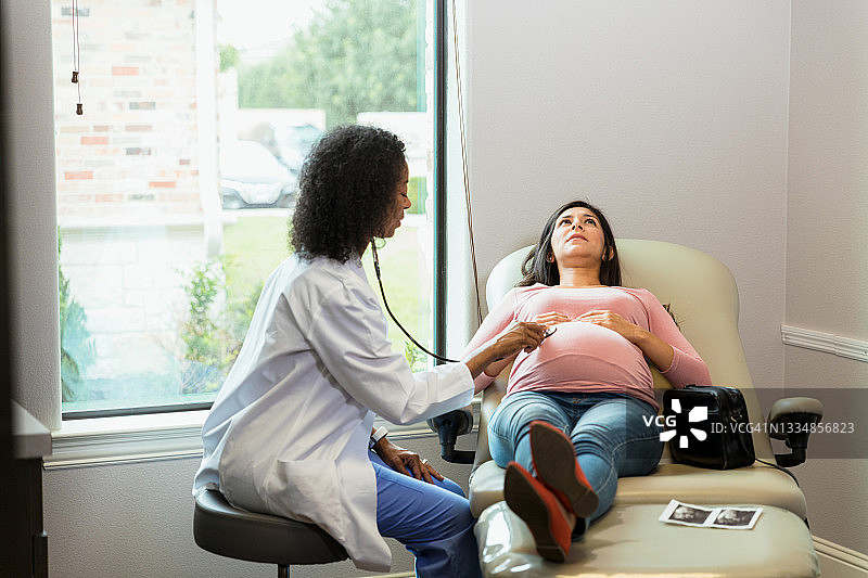 医生用听诊器为孕妇检查时，一旁等待的女人图片素材