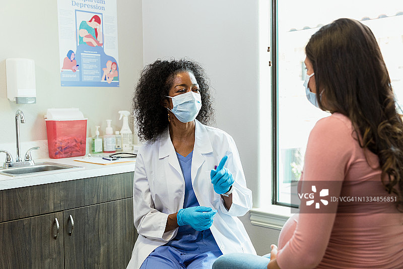 戴口罩的医生为孕妇提供建议图片素材