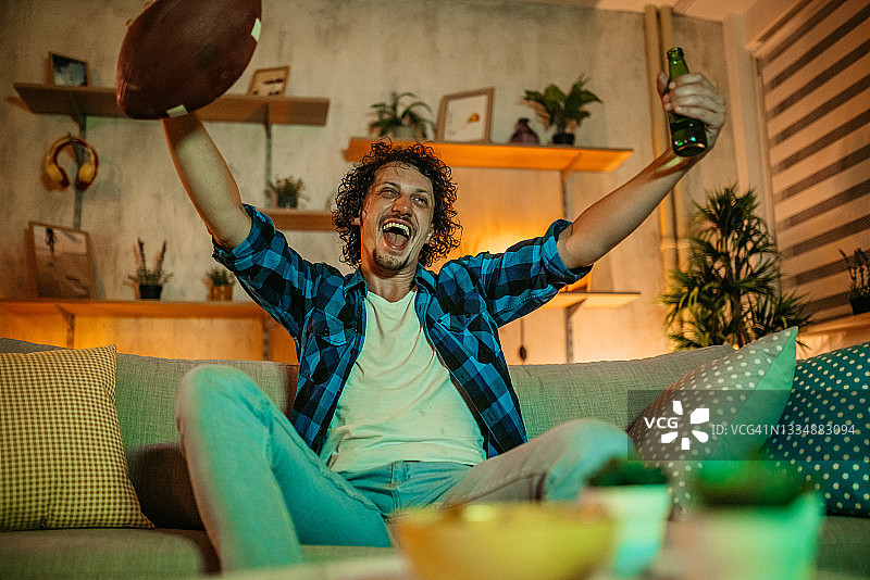 快乐的男人在电视上看美式橄榄球比赛图片素材