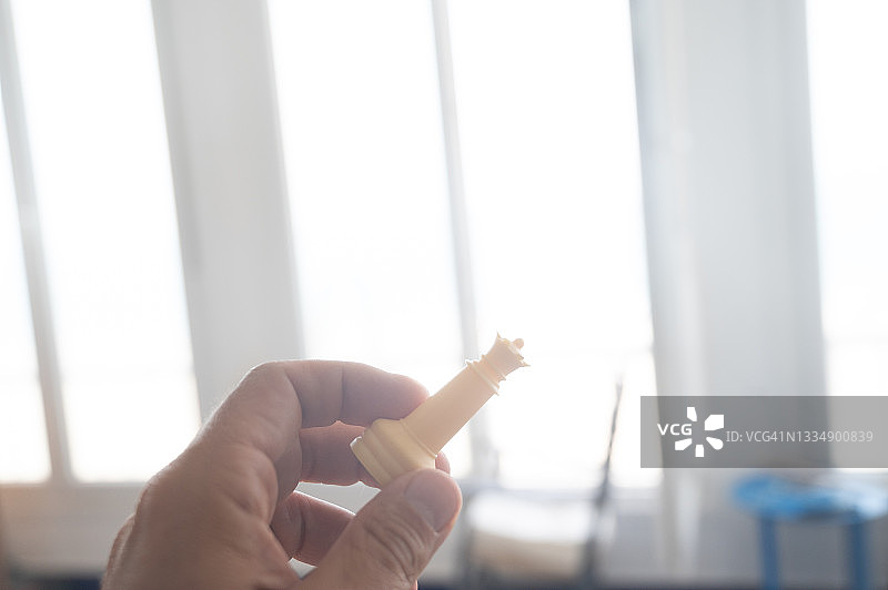 一个人在一栋明亮的房子里，手里拿着一枚棋子，国王图片素材