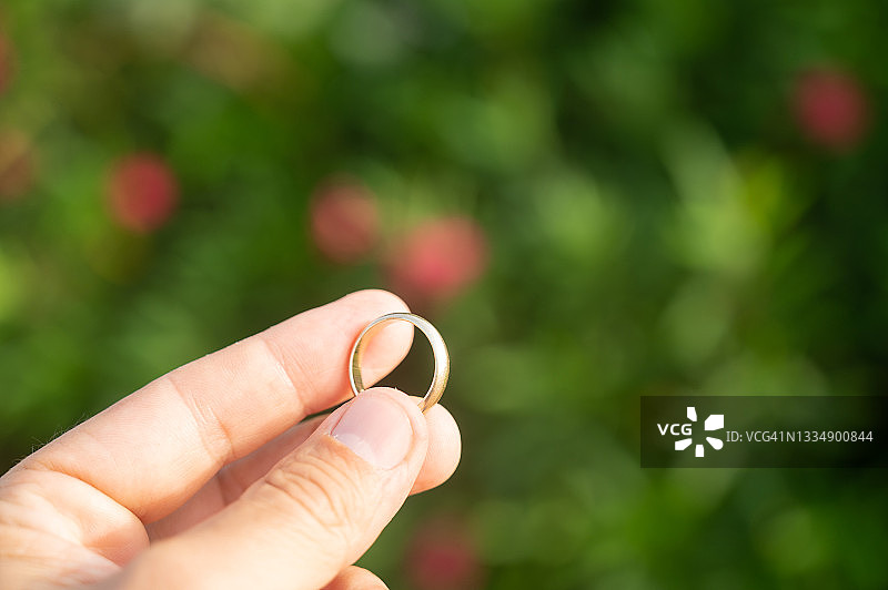 一个人在户外手持一枚金色结婚戒指图片素材