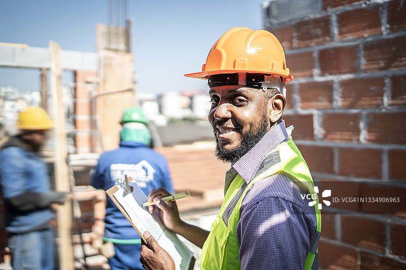 建筑工人手持写字板在建筑工地工作图片素材
