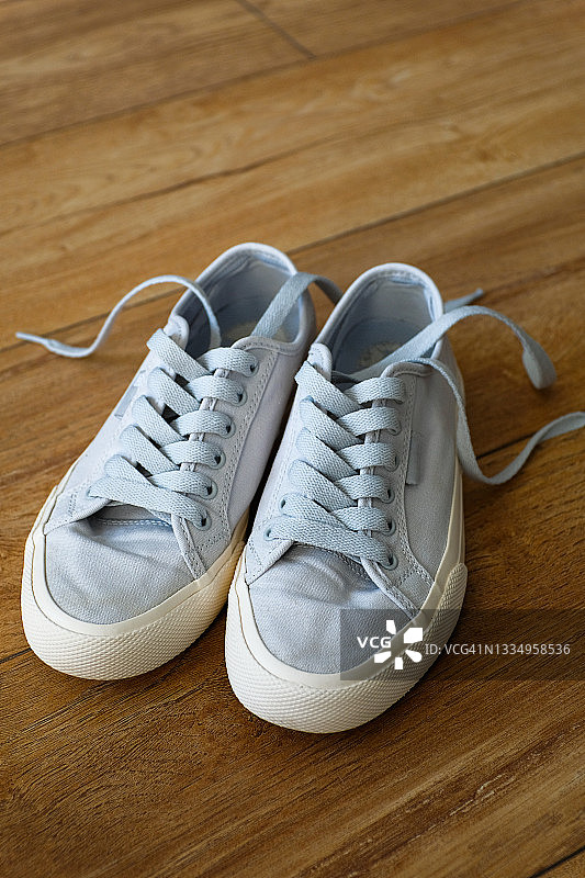适合女性、青少年或女孩的全新干净现代运动鞋。家或室内木地板上的鞋子。时尚的生活方式。文本空间副本。图片素材