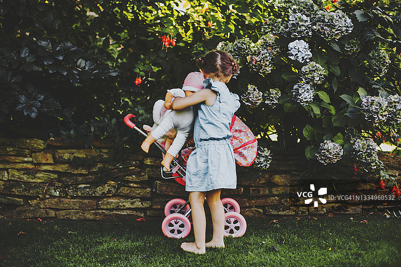 小女孩在户外玩橡胶娃娃的背影图片素材