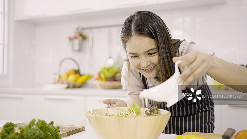 女人往沙拉碗里倒酱汁图片素材