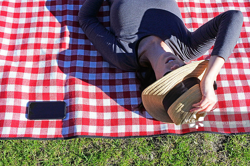 在手机旁的野餐垫上放松的女人图片素材