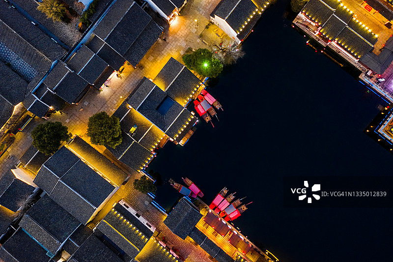 夜幕降临，湖边的房屋亮了起来。无人机俯视角度。中国江苏省无锡市荡口古镇。图片素材