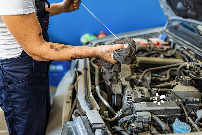 汽车修理工检查发动机油以进行维护图片素材