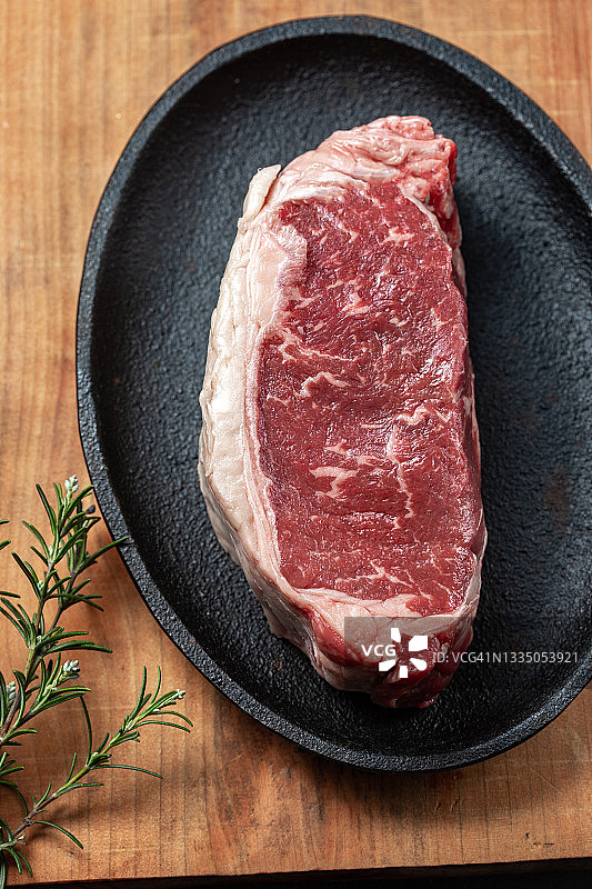 铸铁盘上的生牛里脊肉，配有迷迭香、大蒜和油图片素材