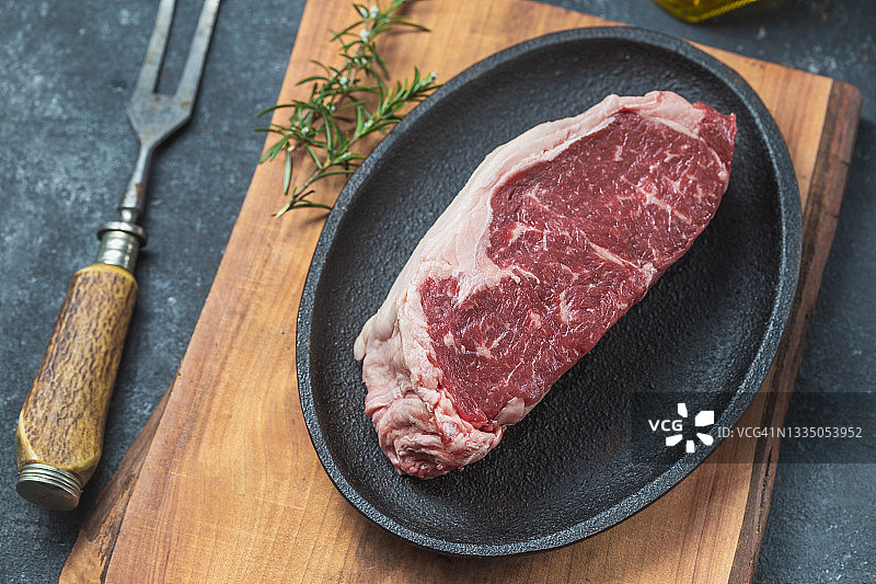 铸铁盘上的生牛里脊肉，配有迷迭香、大蒜和油图片素材