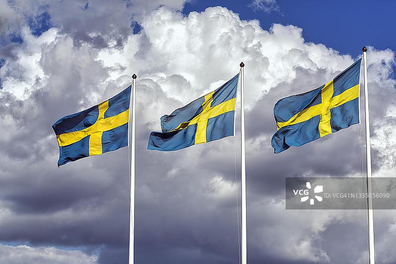 三面瑞典国旗，并排排列，戏剧性的云彩，贝里斯水闸，山脉，林雪平，厄斯特约特兰，瑞典图片素材