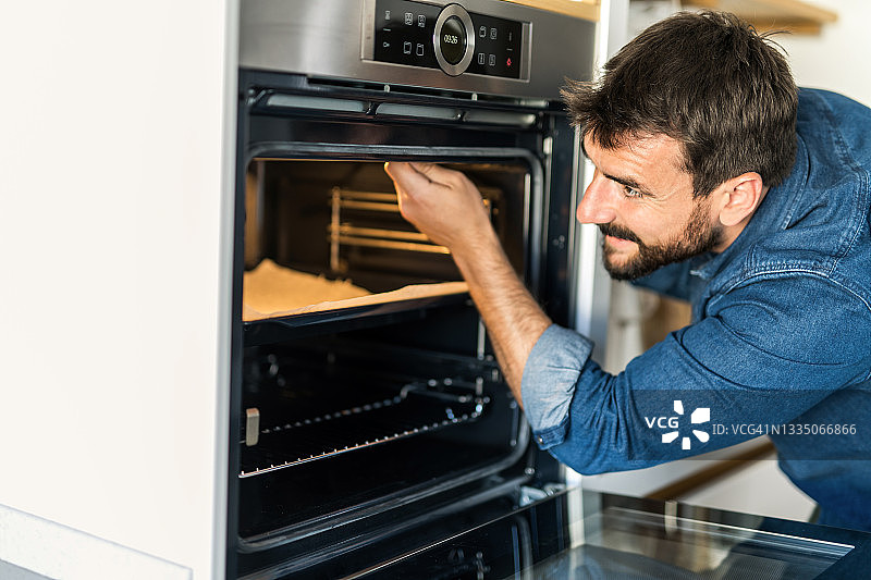 年轻人在家修理烤箱图片素材