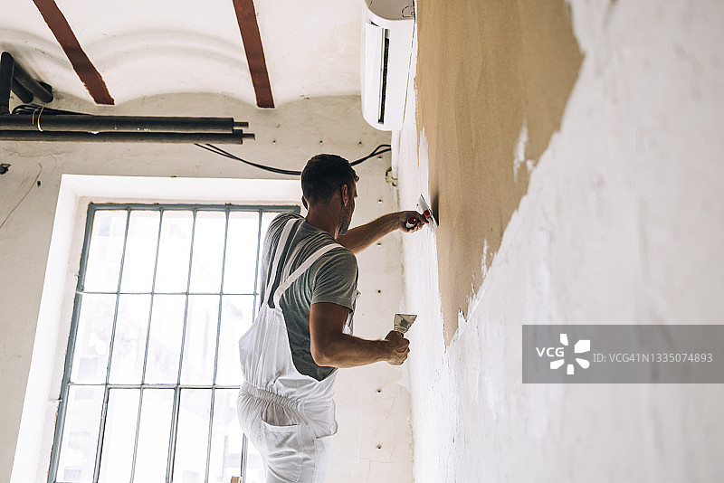 在家用刮刀抹灰的匿名男人图片素材