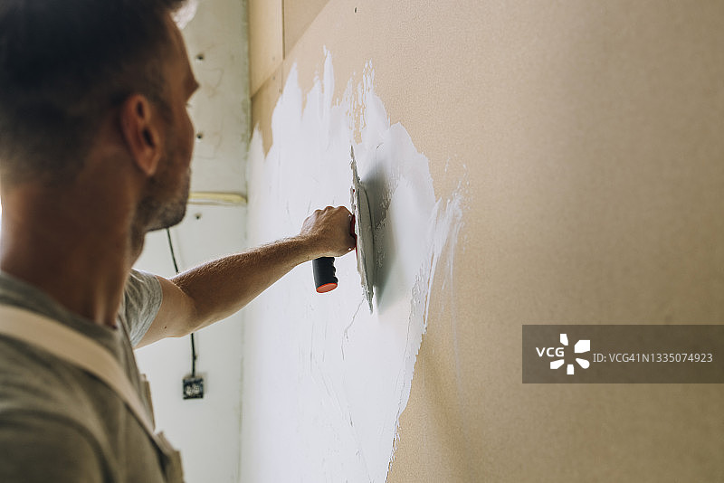 用刮刀在墙上抹灰的匿名男子特写照片图片素材