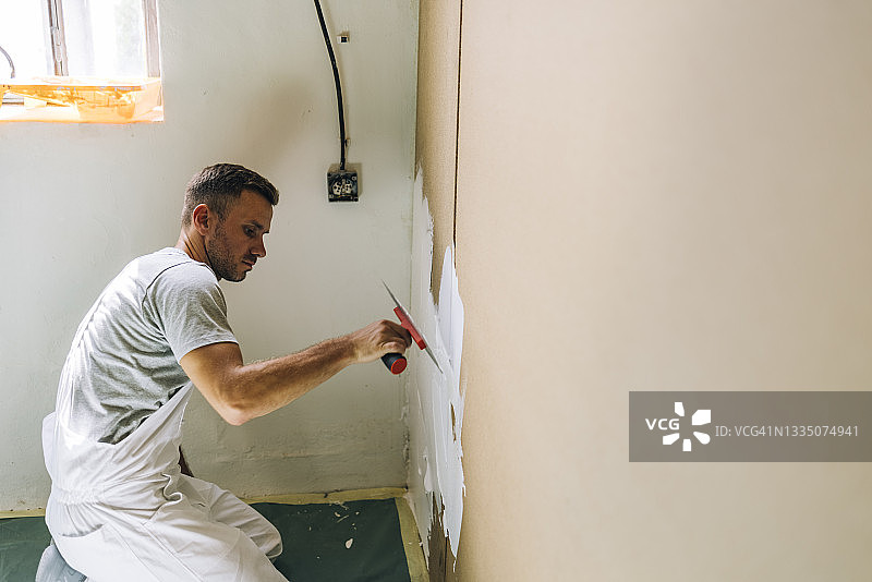 在他工作室里抹灰墙的年轻男人图片素材