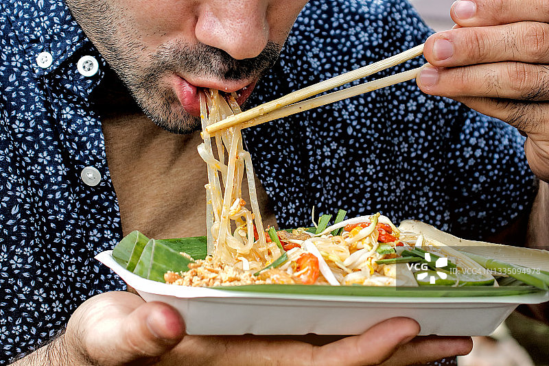 游客品尝泰式炒河粉，泰国传统街头美食图片素材